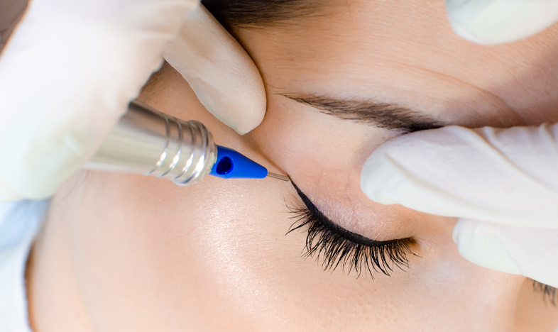 Cosmetologist applying permanent make up eyeliner, eyeliner tattoo procedure